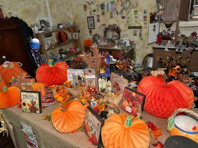 Orange pumpkins, autumn signs, baskets, and other seasonal decorations fill a display table.