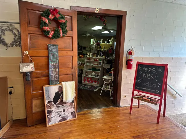 An open classroom doorway and a red chalkboard sign welcome visitors to the Eagles Nest collectibles and craft area.