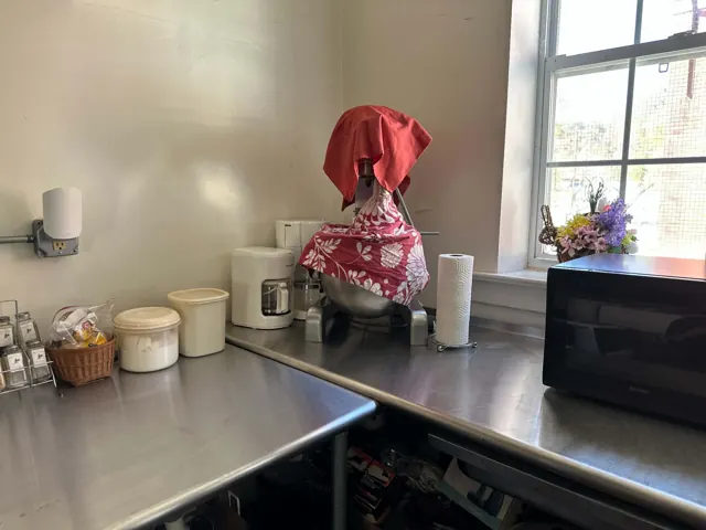 A large covered mixer, coffee makers, and a microwave sit on stainless steel work counters.