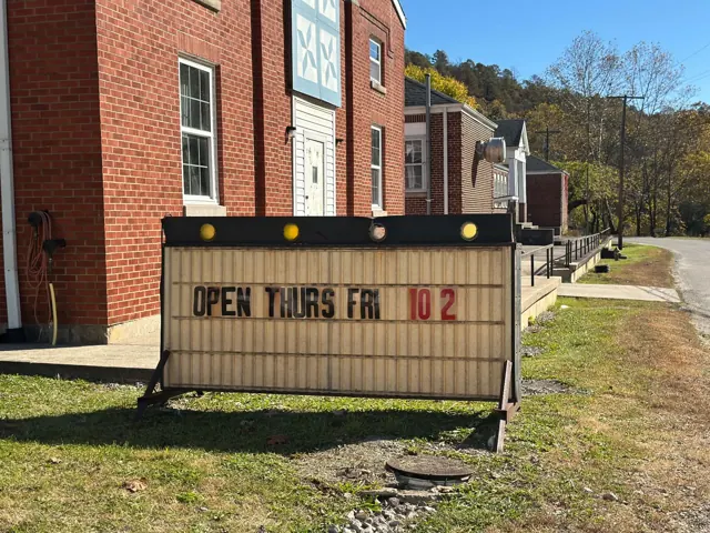 A sign outside the red brick school reads Open Thurs Fri 10 2.