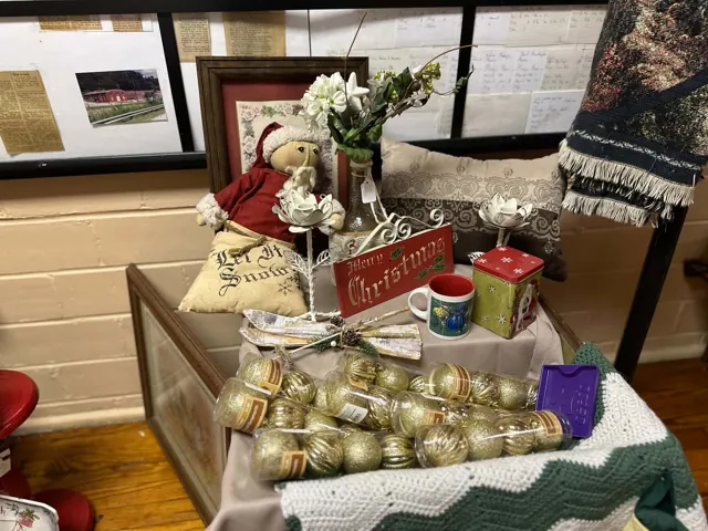 A display includes Christmas decorations, mugs, ornaments, and textiles in front of the center history display.