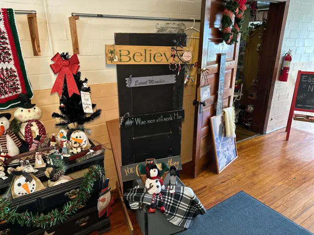 Holiday signs, snowmen, a small tree, and other decorative items stand beside the Eagles Nest doorway.