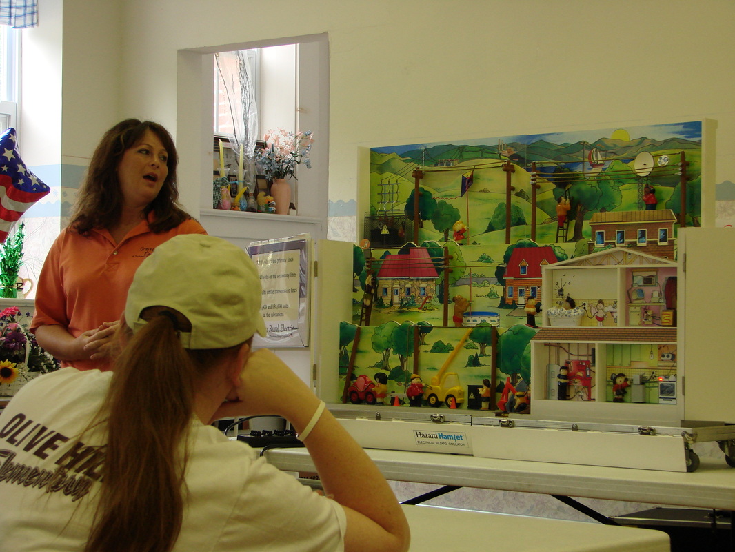 An adult speaking to a group in a classroom with learning displays.