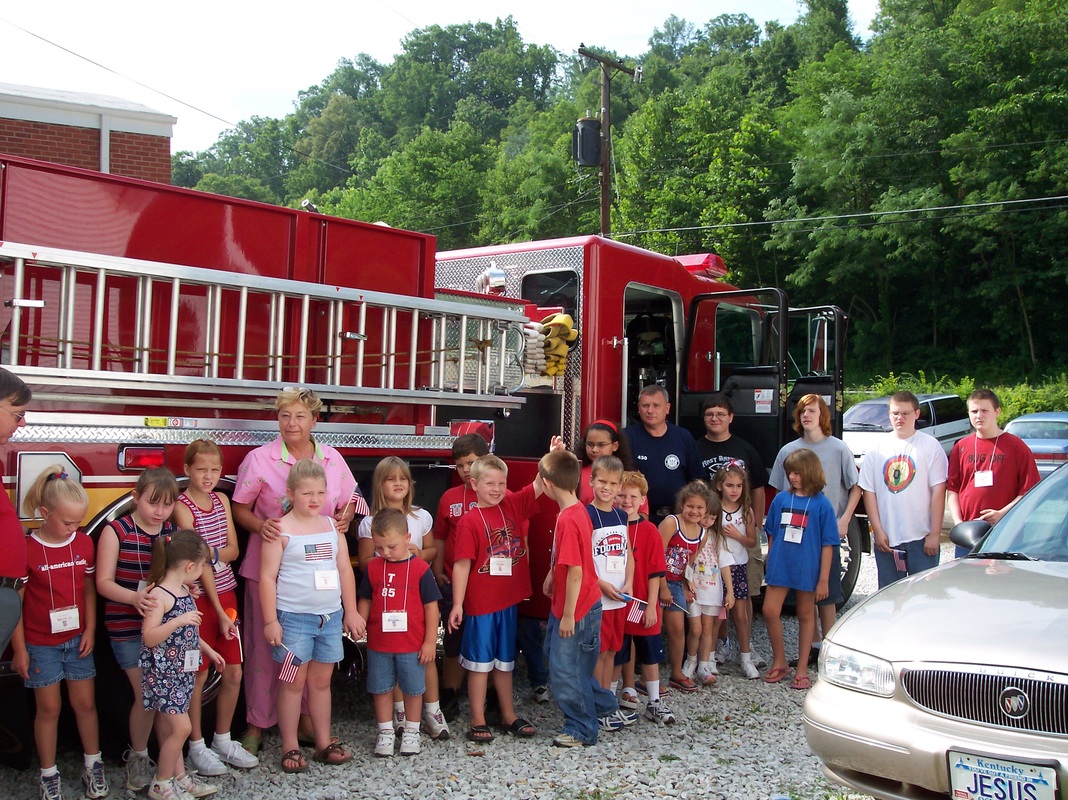 Children and adults gathered beside a red fire truck.