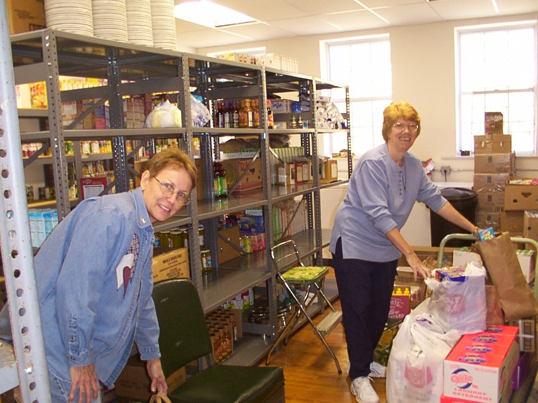 Two people among shelves of food and prepared bags at the center.