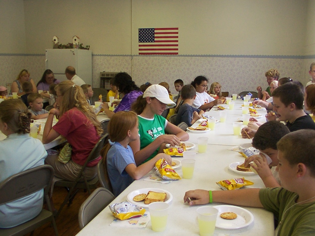 Children and adults sharing a meal at a long table.