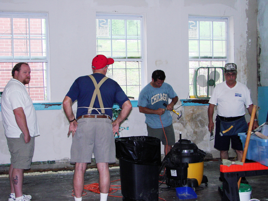 Four volunteers working on the interior of a former classroom.
